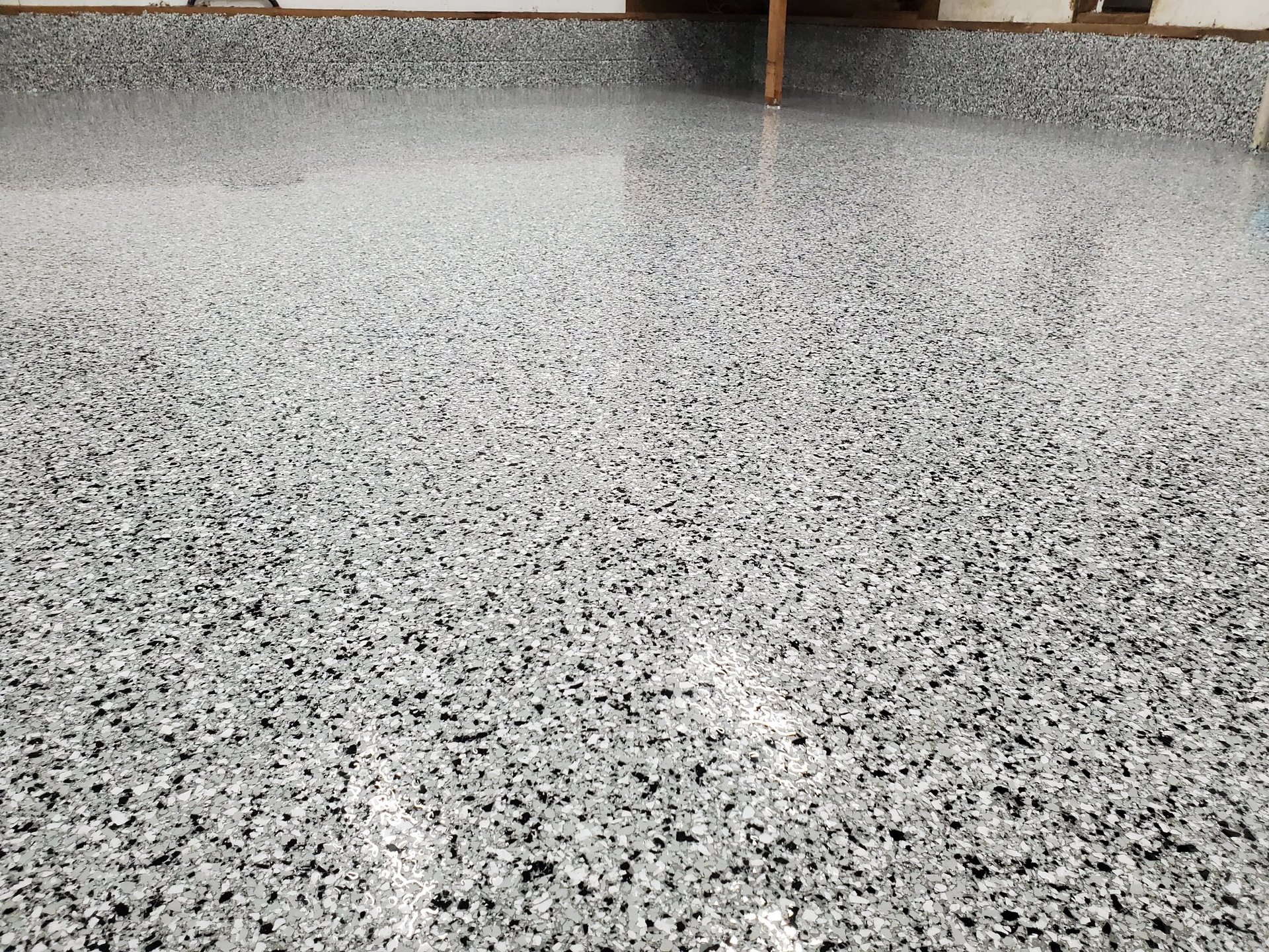 Polished concrete floor with speckled aggregate pattern and wooden support beam