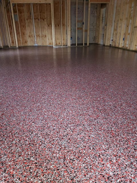 Empty garage interior with polished epoxy floor and wooden stud framing walls during construction