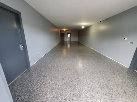 Empty garage interior with polished concrete floor, gray walls, and ceiling lights