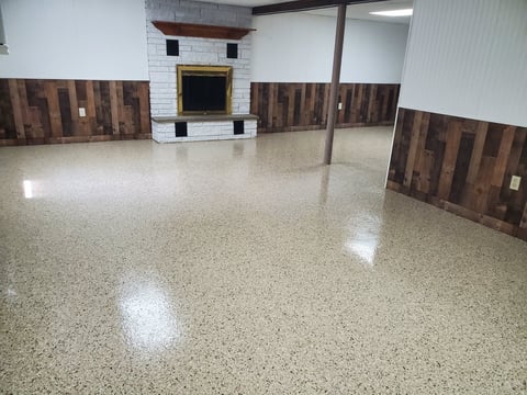 Empty basement room with polished concrete floor, white subway tile and wooden wall accents, fireplace, and support column