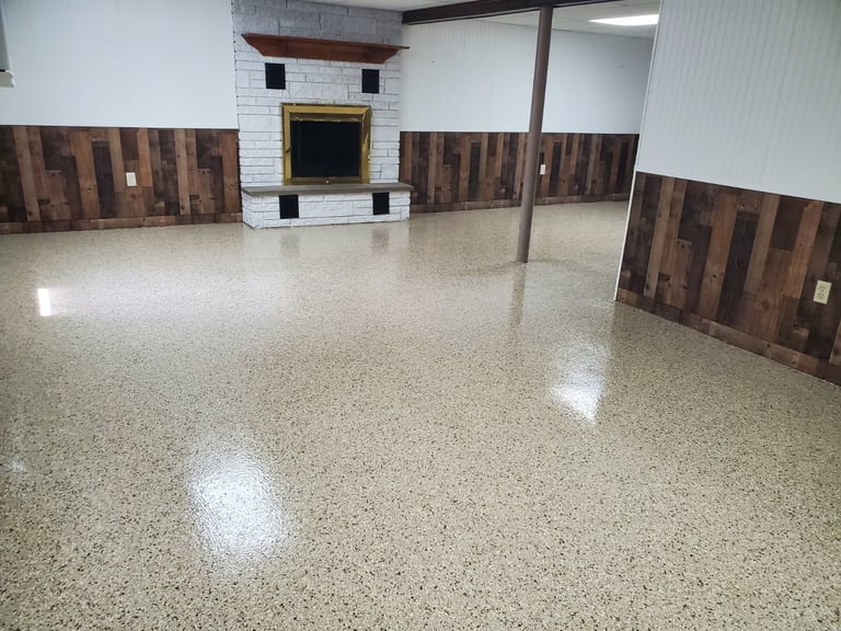 Empty basement room with polished concrete floor, white subway tile and wooden wall accents, fireplace, and support column